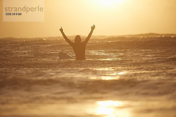 Silhouette eines jungen Surfer mit erhobenen Armen  Devon  England  UK