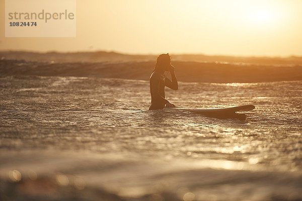 Silhouette eines jungen Surfer und Surfbrettes im Meer  Devon  England  UK