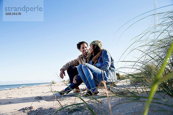 Junges Paar entspannt am Strand  von Angesicht zu Angesicht  lächelnd