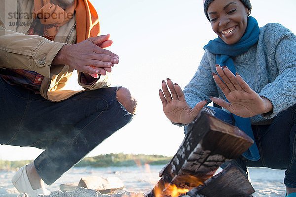 Freunde wärmende Hände über dem Lagerfeuer