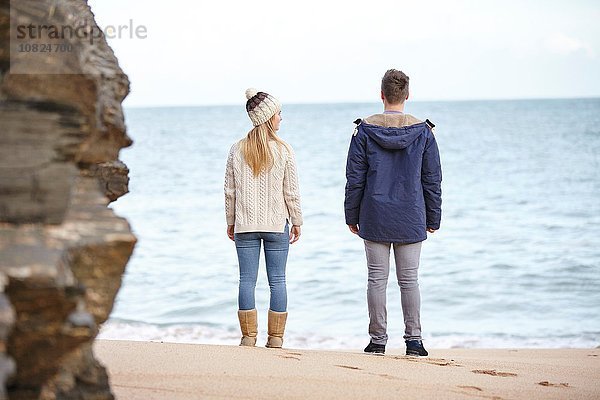 Rückansicht des jungen Paares vom Strand aus  Constantine Bay  Cornwall  UK