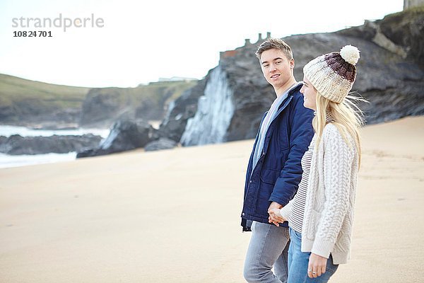 Junges Paar  das Hand in Hand am Strand spazieren geht  Constantine Bay  Cornwall  UK