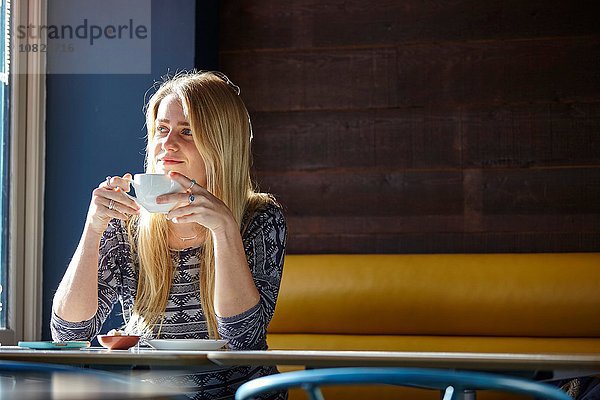 Junge Frau allein im Café beim Kaffeetrinken