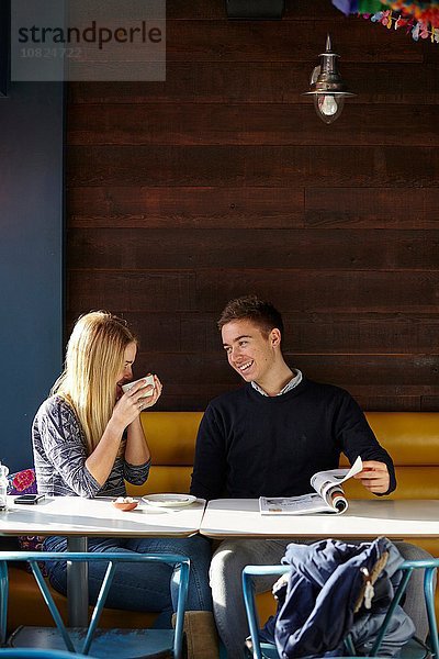 Junges Paar auf Date im Cafe beim Kaffeetrinken und Lesemagazin