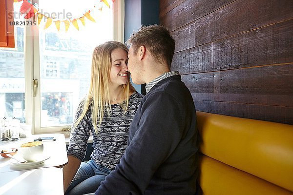 Romantisches junges Paar von Angesicht zu Angesicht im Café-Fenstersitz