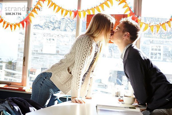 Romantisches junges Paar beim Küssen im Café-Tisch