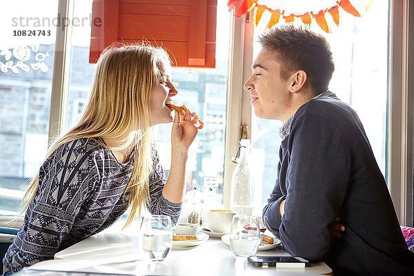 Romantisches junges Paar beim Mittagessen im Café-Fenstersitz