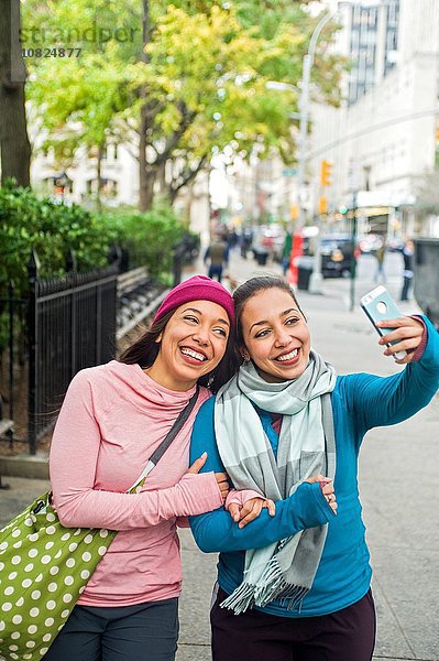 Zwillinge gehen und nehmen Selfie mit smartphone im Park