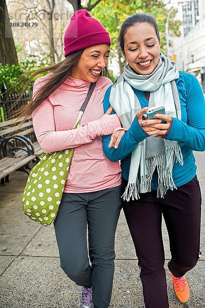 Zwillinge zu Fuß und mit Smartphone im Park