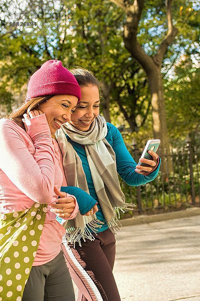 Zwillinge zu Fuß und mit Smartphone im Park