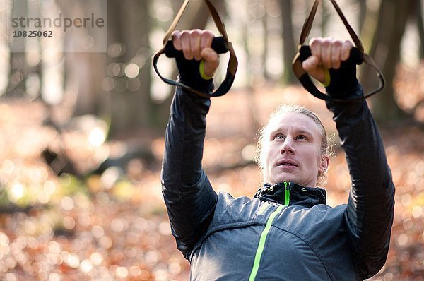 Mittlerer erwachsener Mann mit Widerstandsbändern  nach oben schauend