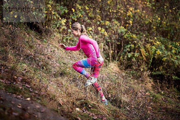 Seitenansicht der jungen Frau in Sportbekleidung beim Bergauflaufen