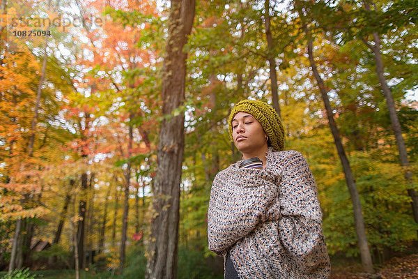 Mittlere erwachsene Frau im Herbstwald in Schal gehüllt