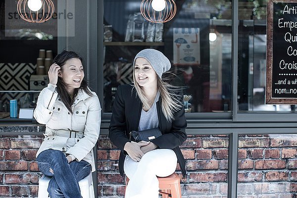 Zwei Freundinnen sitzen vor dem Stadtcafé.