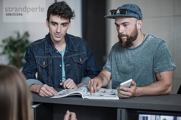 Zwei junge Männer  die an der Rezeption nachfragen.