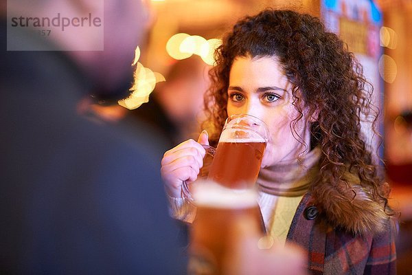 Junge Frau am Abend beim Bier trinken