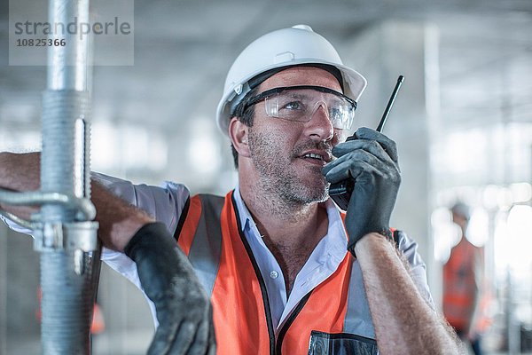 Mittlerer Erwachsener männlicher Bauleiter mit Walkie-Talkie auf der Baustelle