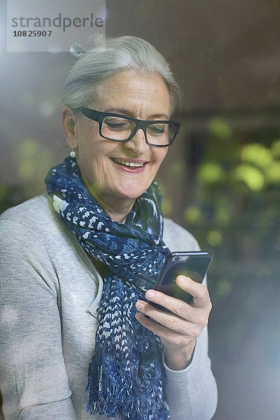 Reife Frau lächelt über die Nachricht auf dem Smartphone