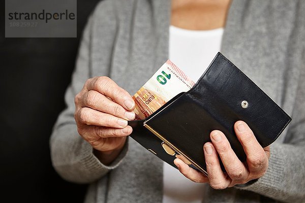 Eine Frau  die Geld aus ihrer Brieftasche holt.