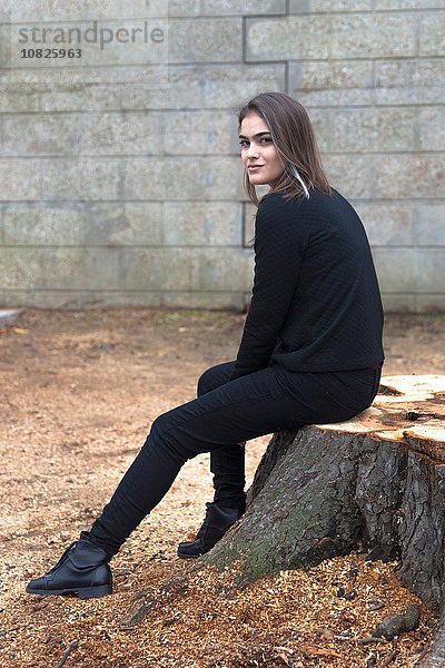 Junge Frau auf Baumstumpf sitzend