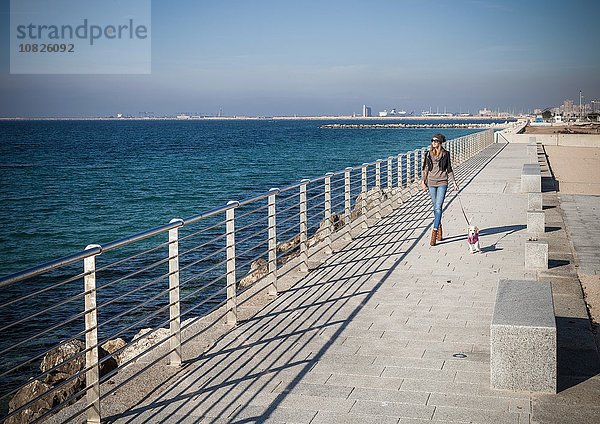 Durchgehende Vorderansicht junge Frau  die am Meer spazieren geht  schaut weg.