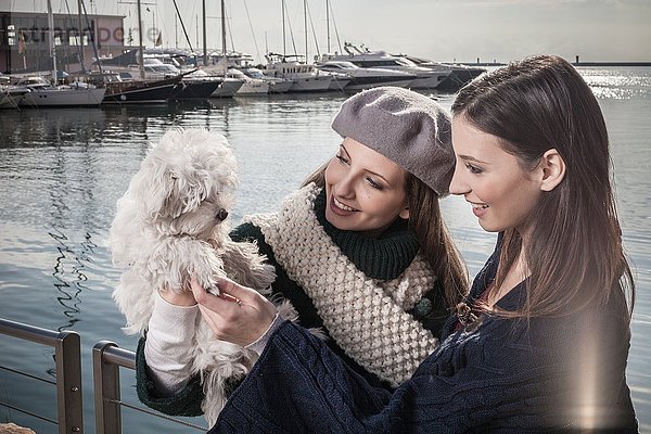 Junge Frauen in der Werft halten Hund lächelnd hoch