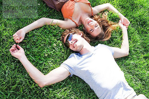 Draufsicht auf ein romantisches junges Paar  das auf einer Gartenwiese liegt.