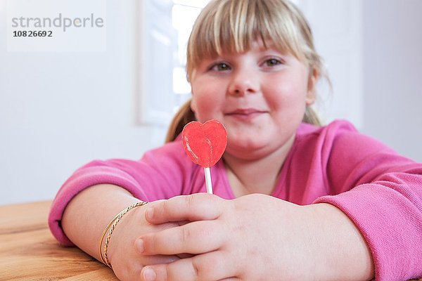 Porträt eines übergewichtigen Mädchens mit Herzform Lollipop