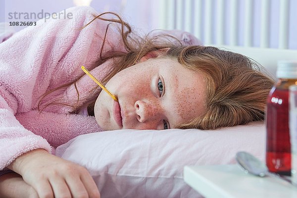Nahaufnahme des im Bett liegenden Mädchens mit Thermometer im Mund