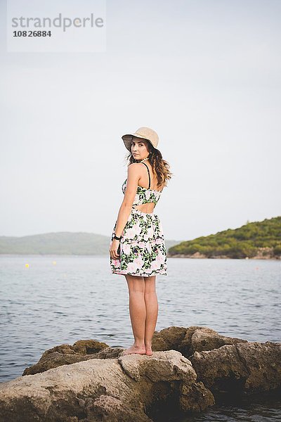 Frau auf Felsen am Meer stehend