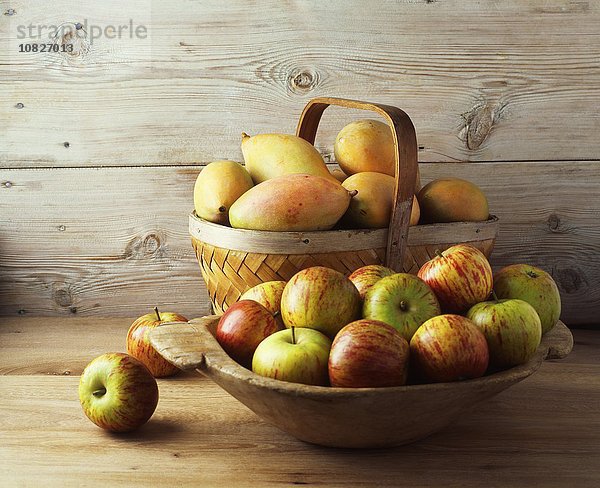 Schale und Korb mit Äpfeln und Mangos