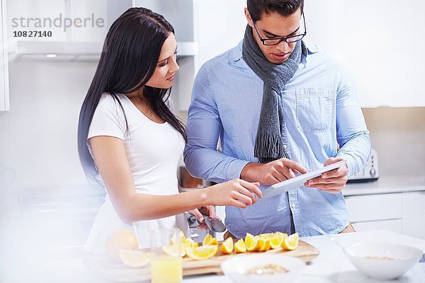 Junges Paar mit digitalem Tablett an der Küchenzeile