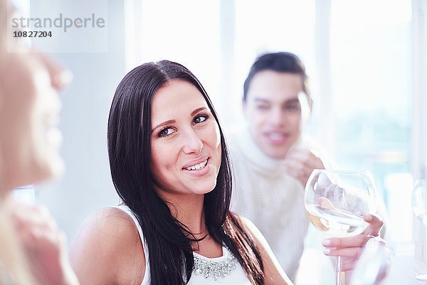 Beschnittene Ansicht von drei jungen erwachsenen Freunden  die in der Küche plaudern und Wein trinken.