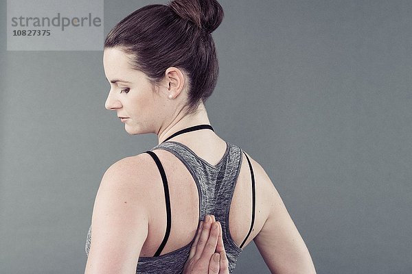 Junge Frau beim Yoga  grauer Hintergrund