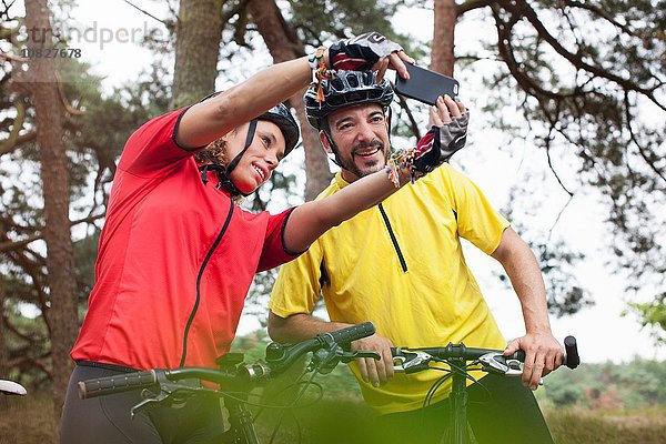 Glückliches Mountainbike-Pärchen mit Smartphone-Selfie im Wald