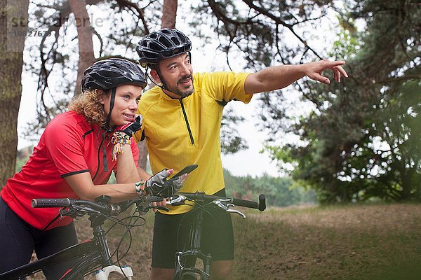 Mountainbike-Paar mit Smartphone-Navigation im Wald