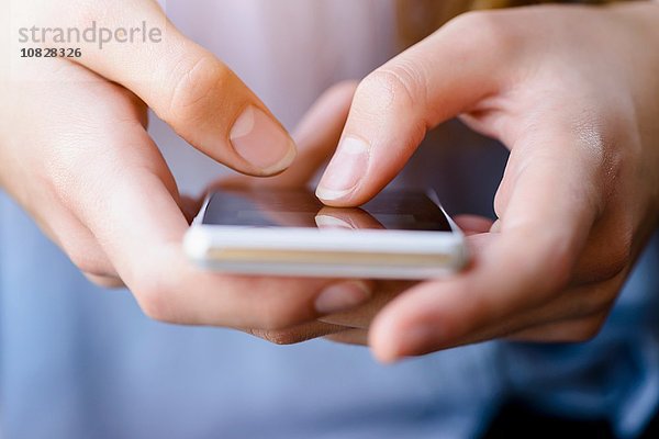 Beschnittene Ansicht von jungen Frauen beim SMSen auf dem Smartphone