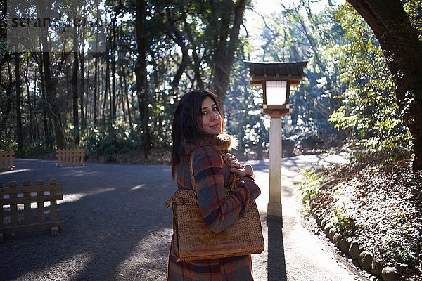 Porträt einer reifen Touristin mit Blick über die Schulter im Park  Tokio  Japan