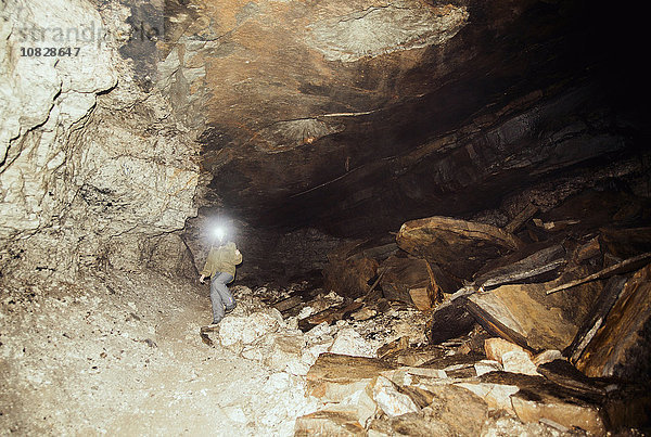 Kaukasischer Wanderer mit Stirnlampe in einer Höhle