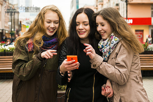 Kaukasische Frauen  die im Freien ein Mobiltelefon benutzen