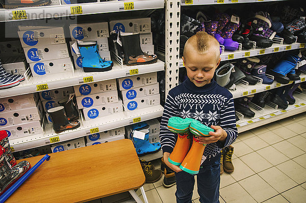 Kaukasischer Junge bewundert Stiefel im Geschäft