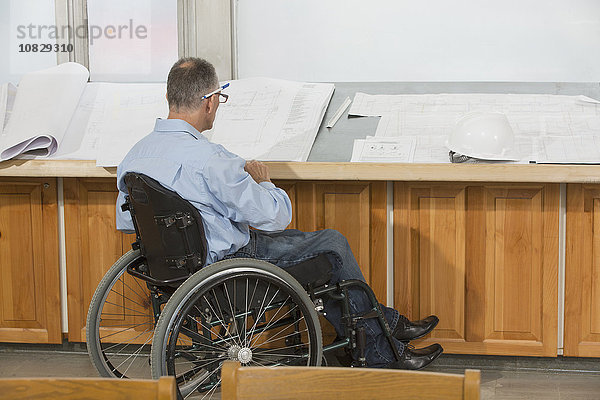Kaukasischer Architekt im Rollstuhl im Gespräch im Büro