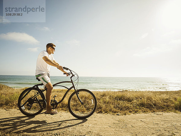 Kaukasischer Mann fährt Fahrrad am Strand