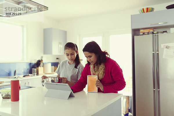 Mutter und Tochter benutzen ein digitales Tablet in der Küche