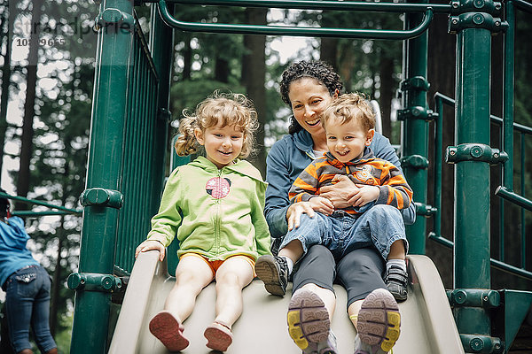 Kaukasische Mutter und Kinder spielen auf dem Spielplatz