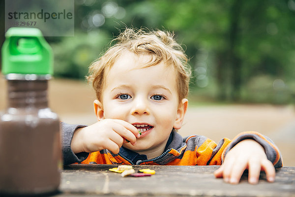 Kaukasischer Junge isst Snack am Picknicktisch