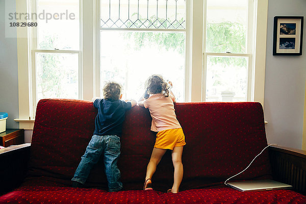 Kaukasische Kinder stehen auf dem Sofa