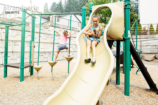 Gemischtrassige Schwestern spielen auf dem Spielplatz