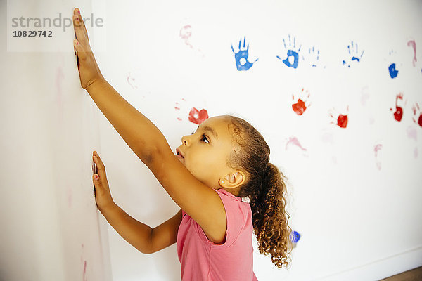 Gemischtrassiges Mädchen macht Handabdrücke an der Wand