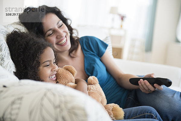 Mutter und Tochter sehen auf dem Sofa fern